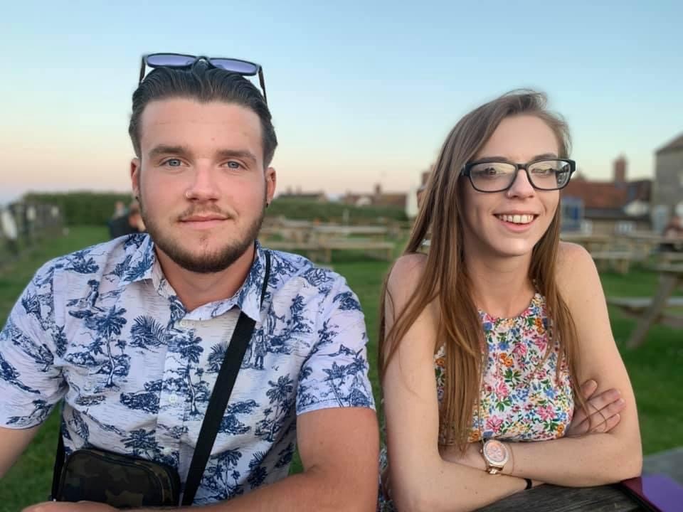 two young adults sitting on a bench 